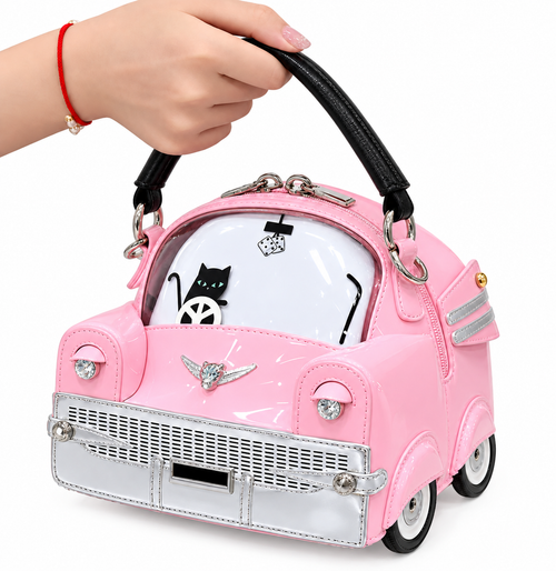 A pink car-shaped handbag with a black handle, held by a hand. The bag features a glossy pink faux leather exterior, a white hood with a black cat graphic, silver chrome details, and black and white wheels.