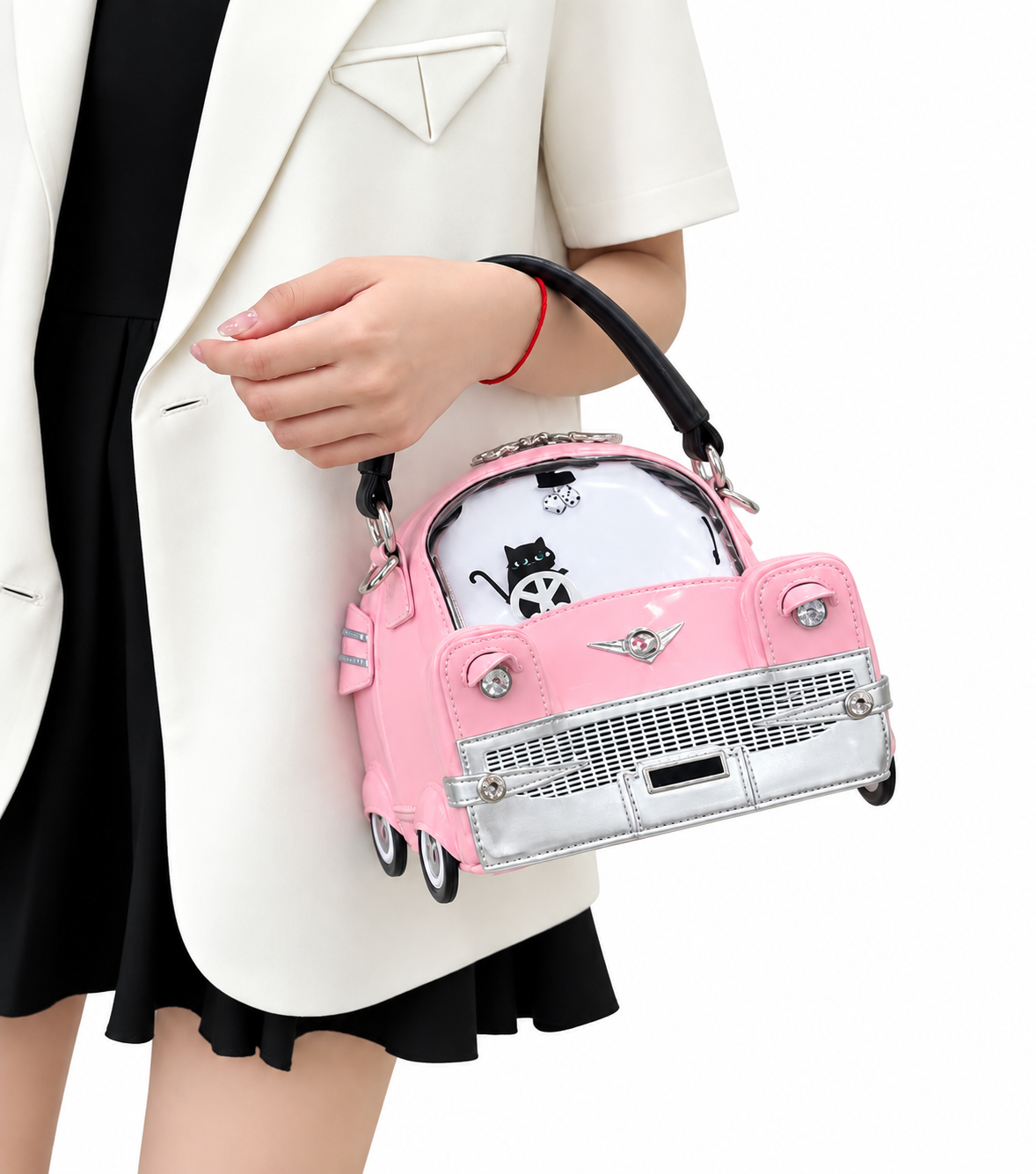 A pink car-shaped handbag with silver trim and a black handle, carried by a model wearing a white blazer and black dress against a white background.